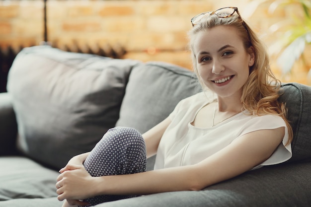 Hermosa mujer posando en el sofá, interior casa