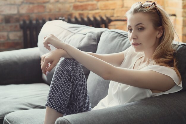 Hermosa mujer posando en el sofá, interior casa