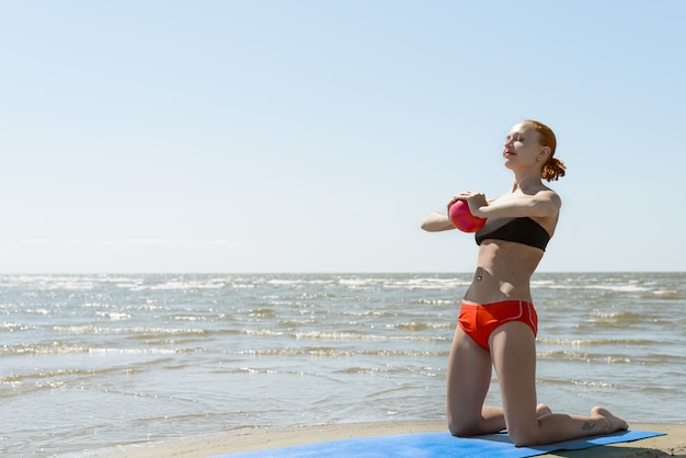 Hermosa mujer practicando fitness en el mar