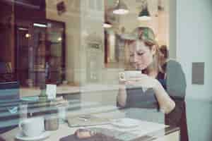Foto gratuita hermosa mujer que huele a bebida en el café