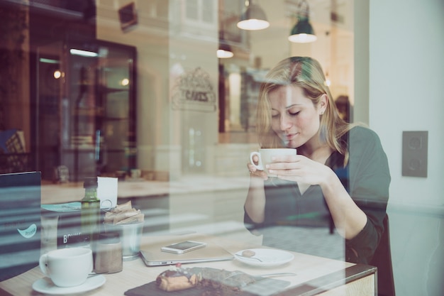 Hermosa mujer que huele a bebida en el café