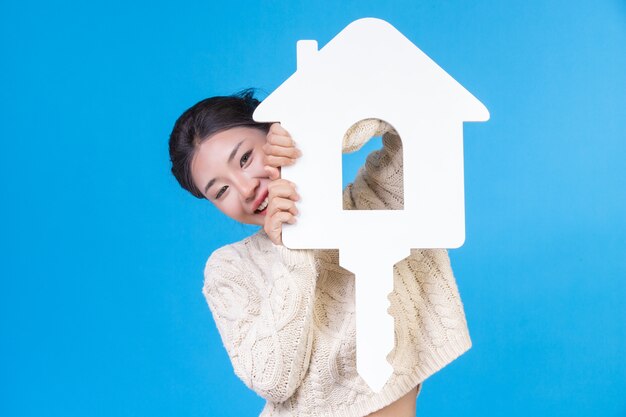 Una hermosa mujer que llevaba una nueva camisa blanca de manga larga con el símbolo de una casa. Comercio de la casa.