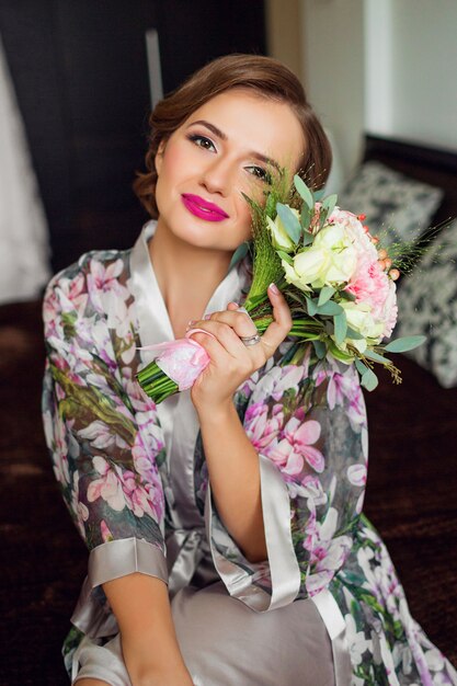 Hermosa mujer recién casada comienza la preparación del día de la boda en bata de baño floral