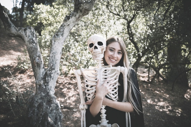 Hermosa mujer riendo abrazando detrás de esqueleto