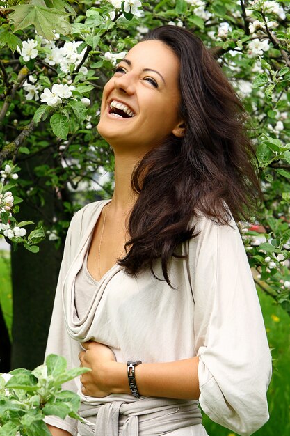 Hermosa mujer riendo por árbol floreciente