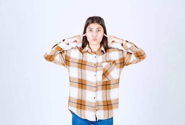 Foto gratuita hermosa mujer en ropa casual tapándose los oídos en la pared blanca.