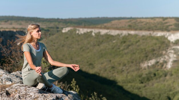 Hermosa mujer rubia haciendo yoga al aire libre