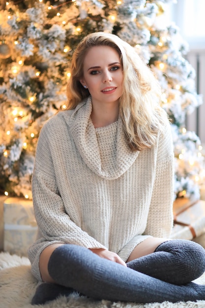 Hermosa mujer rubia junto al árbol de Navidad.