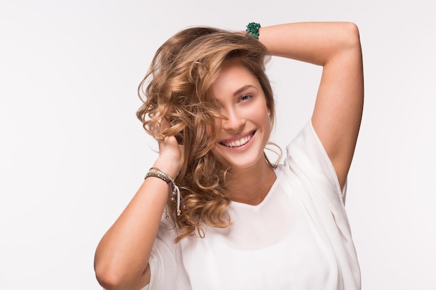 Hermosa mujer rubia con pelo largo y rizado. Señora en camiseta blanca aislada en blanco.