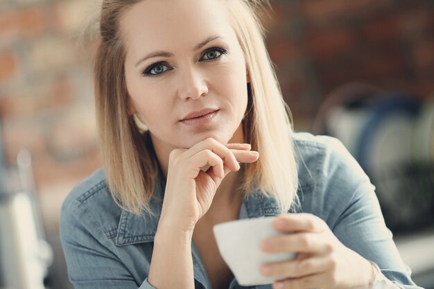 Hermosa mujer rubia posando con taza de café