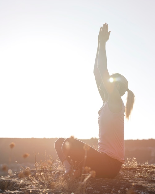 Hermosa mujer rubia practicando yoga al aire libre