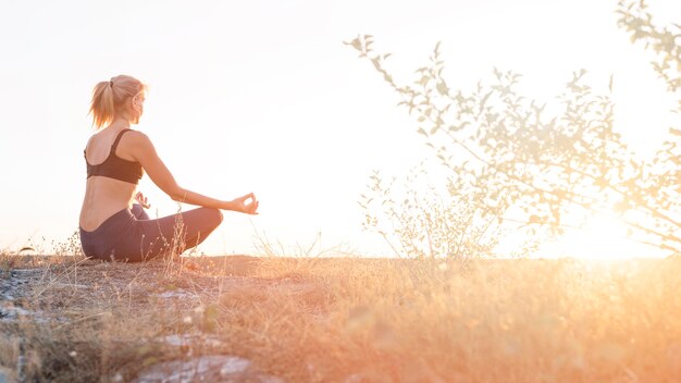 Hermosa mujer rubia practicando yoga al aire libre