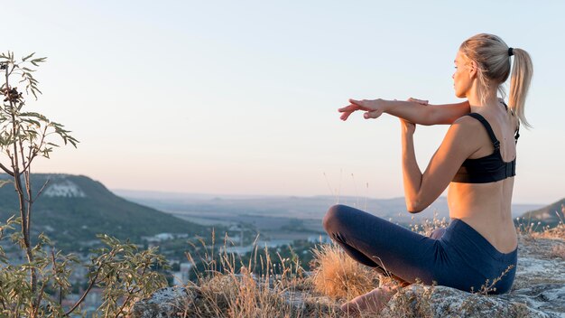 Hermosa mujer rubia practicando yoga al aire libre