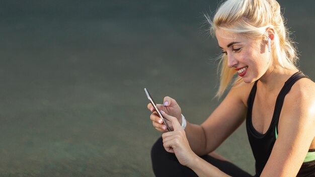 Foto gratuita hermosa mujer rubia revisando su teléfono