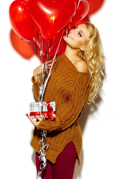 hermosa mujer rubia en suéter acogedor con globos y presentes