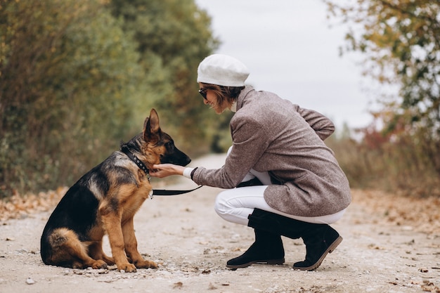 Hermosa mujer saliendo de su perro en el parque otoño