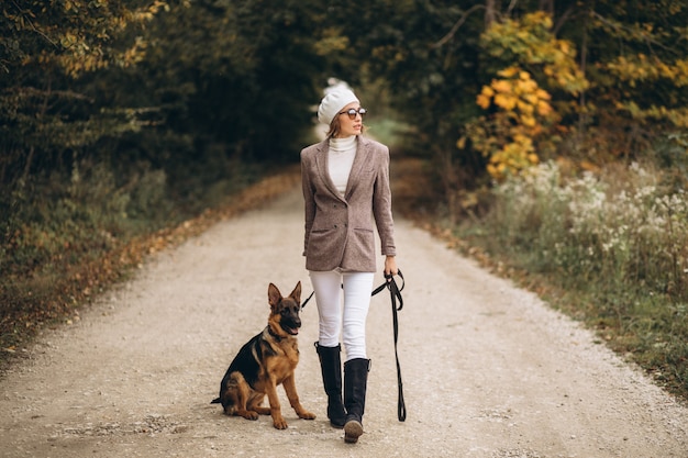 Hermosa mujer saliendo de su perro en el parque otoño