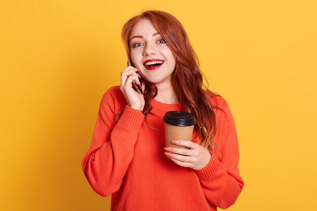 Hermosa mujer satisfecha con mirada emocionada, disfruta de café para llevar caliente