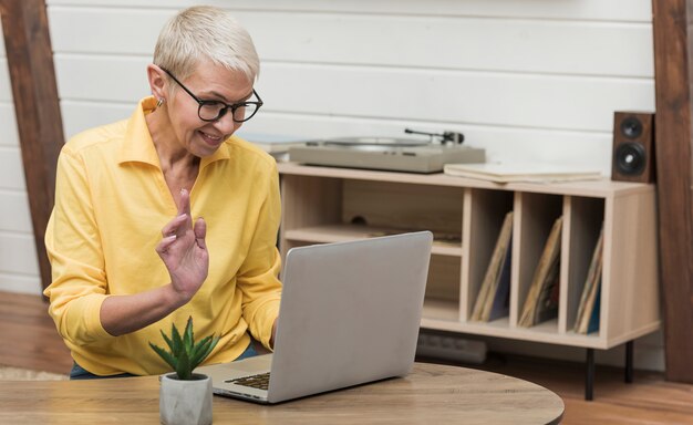 Hermosa mujer senior mirando a través de internet en su computadora portátil