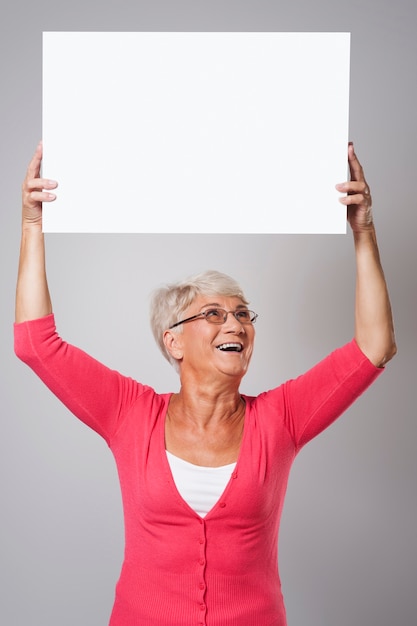 Hermosa mujer senior con pizarra sobre la cabeza