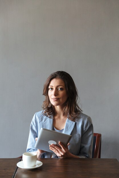 Hermosa mujer sentada en el interior con tablet PC.