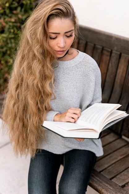 Hermosa mujer sentada y leyendo al aire libre