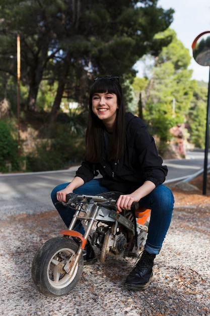 Hermosa mujer sentada en una motocicleta pequeña