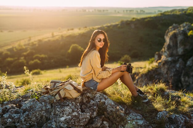 Hermosa mujer sentada en roca sosteniendo binocular