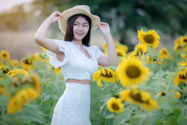 Hermosa mujer sexy con un vestido blanco caminando en un campo de girasoles