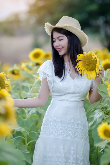 Hermosa mujer sexy con un vestido blanco caminando en un campo de girasoles