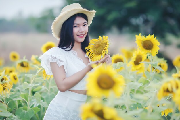 Hermosa mujer sexy con un vestido blanco caminando en un campo de girasoles