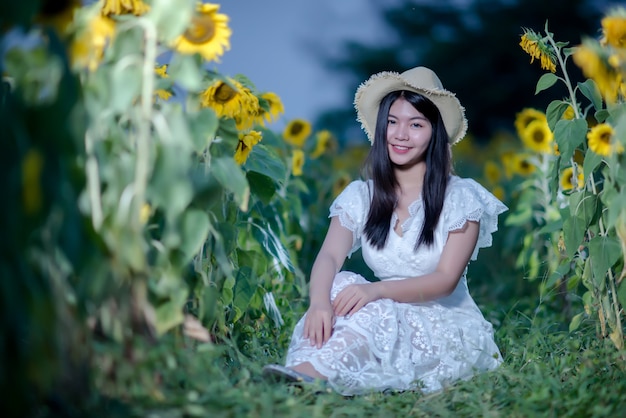 Hermosa mujer sexy con un vestido blanco caminando en un campo de girasoles