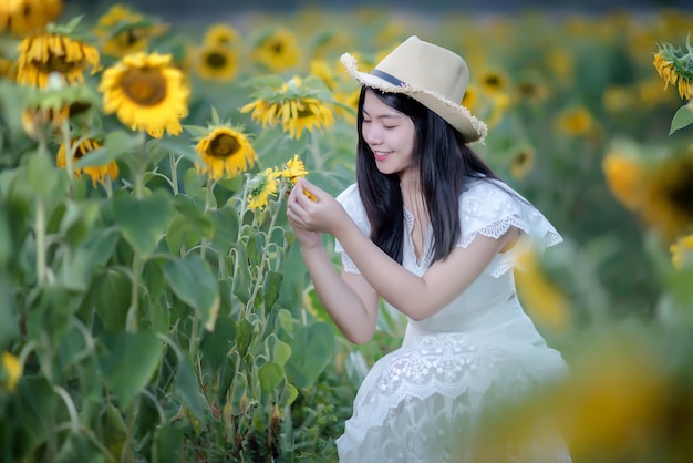 Hermosa mujer sexy con un vestido blanco en un campo de girasoles, estilo de vida saludable
