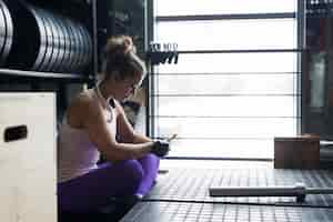 Foto gratuita hermosa mujer con smartphone en el gimnasio