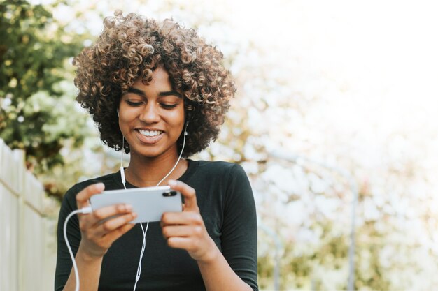 Hermosa mujer con smartphone en el jardín remezclado de medios