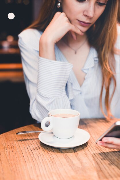 Hermosa mujer con smartphone en mesa de café