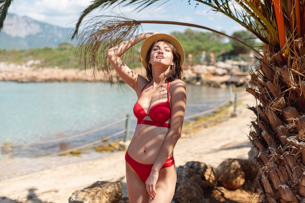 Foto gratuita hermosa mujer con un sombrero cerca de una palmera