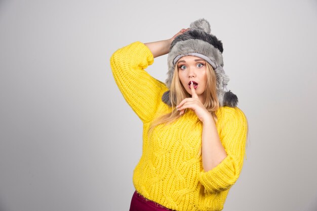 Hermosa mujer con sombrero de invierno haciendo señal de silencio.