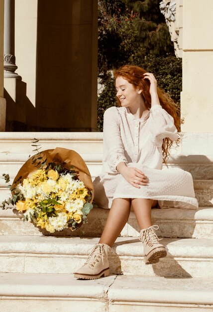 Hermosa mujer sonriente al aire libre con ramo de flores de primavera