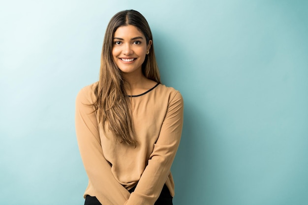 Hermosa mujer sonriente con el pelo largo de pie contra el fondo azul.