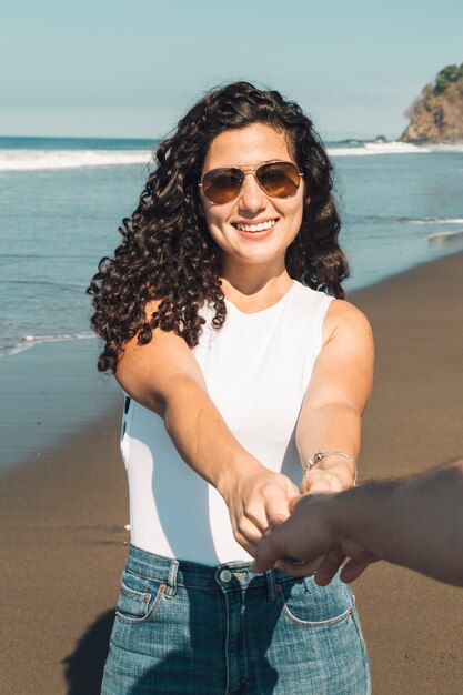 Hermosa mujer sonriente que quiere que su hombre siga a la playa