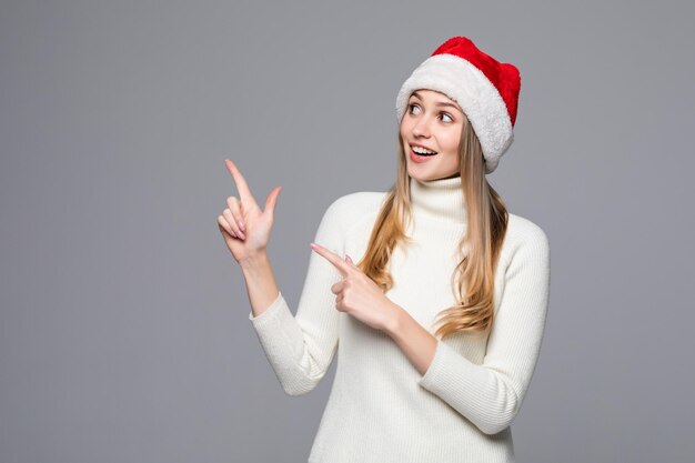 Hermosa mujer sonriente de santa navidad apuntando hacia arriba mostrando copyspace