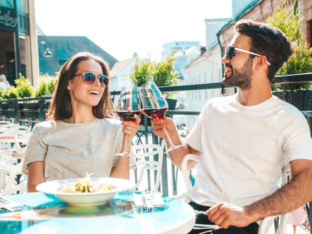 Hermosa mujer sonriente y su apuesto novio Familia feliz y alegre Pareja animando con copas de vino tinto en su cita en el restaurante Beben alcohol en el café de la terraza en la calle