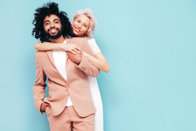 Hermosa mujer sonriente y su guapo novio Familia multirracial alegre y sexy que tiene momentos tiernos sobre fondo azul en el estudio Modelos multiétnicos abrazándose Abrazándose unos a otros Concepto de amor