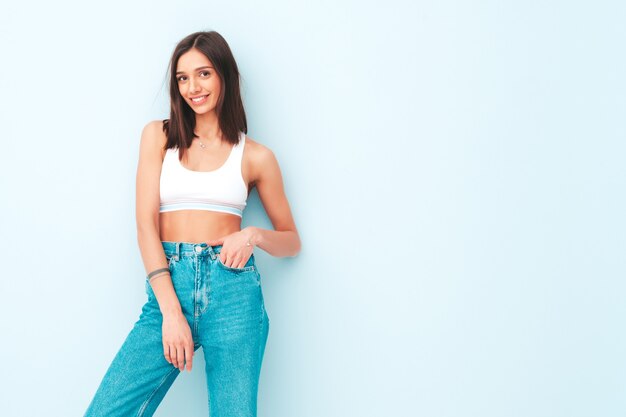 Hermosa mujer sonriente vestida con jeans y camisa de jersey blanco