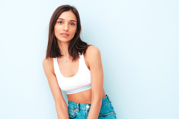 Hermosa mujer sonriente vestida con jeans y camisa de jersey blanco