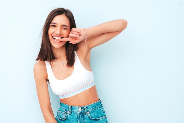 Hermosa mujer sonriente vestida con jeans y camisa de jersey blanco