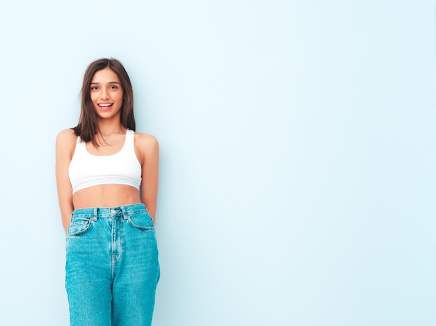 Hermosa mujer sonriente vestida con jeans y camisa de jersey blanco