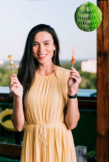 Hermosa mujer sosteniendo aperitivos y sonriendo