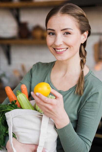 Hermosa mujer sosteniendo la bolsa con verduras orgánicas